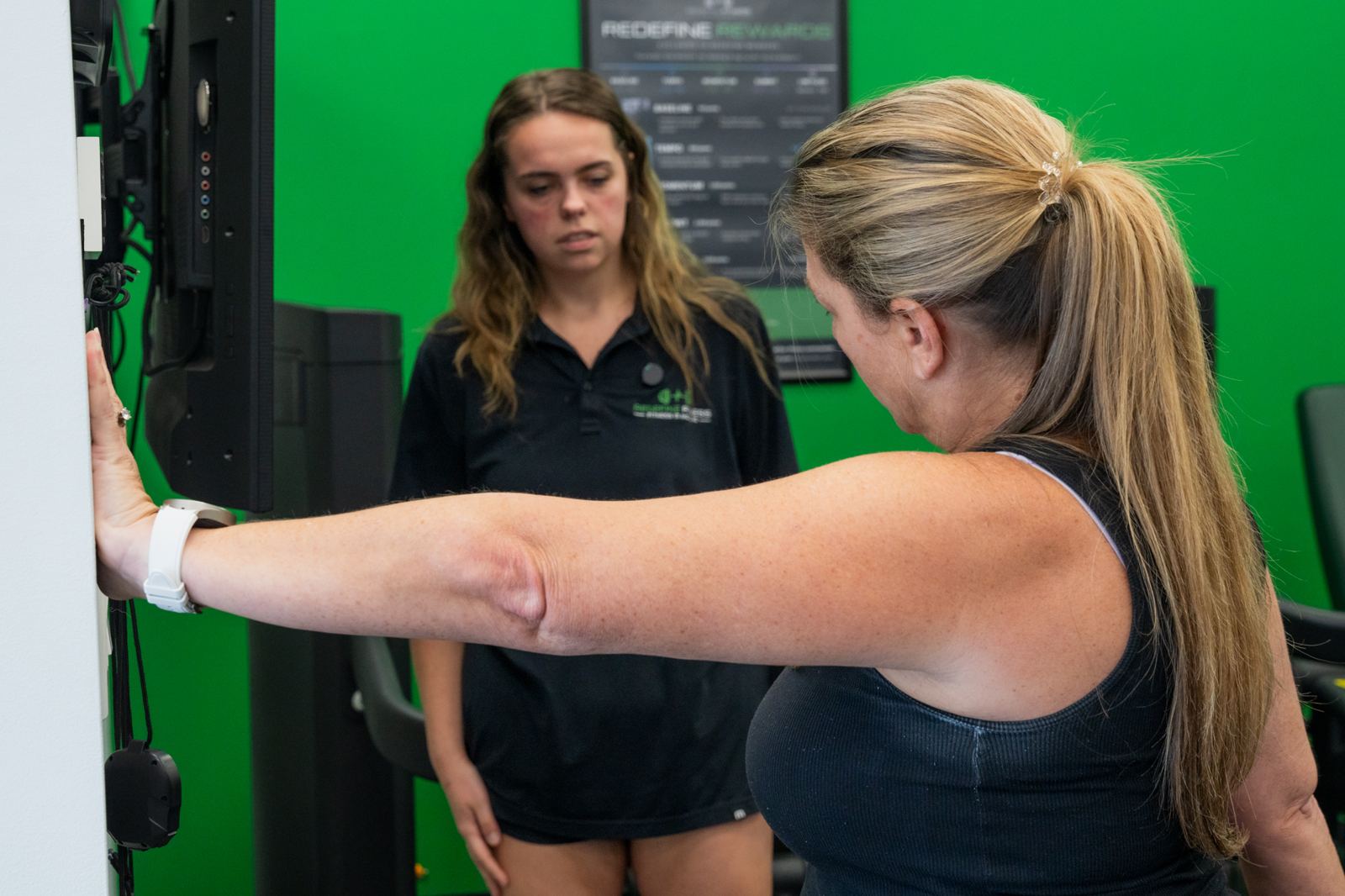 Fitness Specialist watching a client’s shoulder reach during a Redefine Fitness movement screen