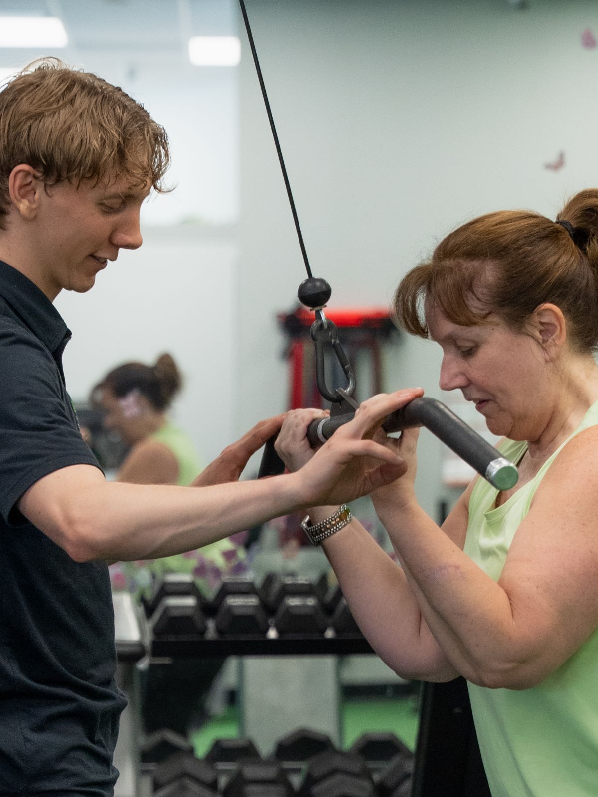 Elite client training one on one with her Fitness Specialist, hands-on coaching at the cable machine