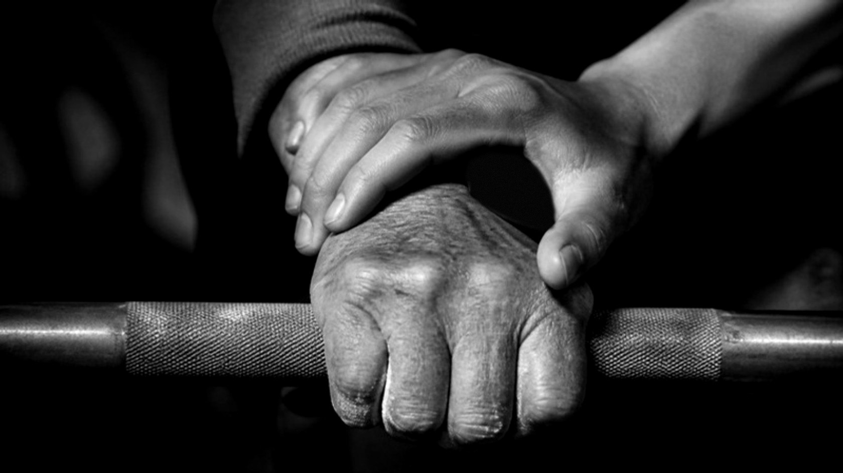 Two hands on a barbell, one steadying the other. The Redefine Standard.
