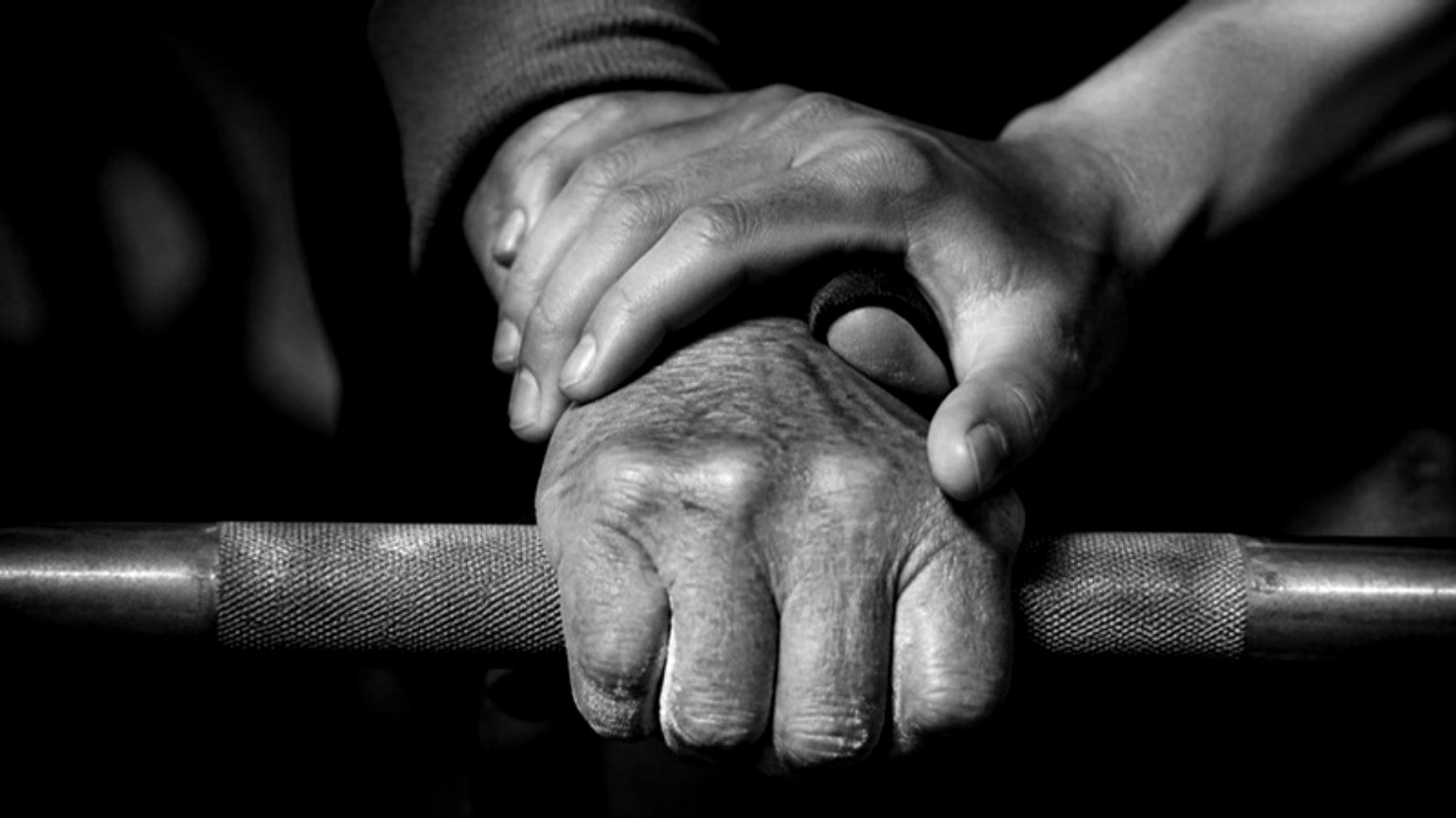 Two hands on a barbell, one steadying the other. The Redefine Standard.